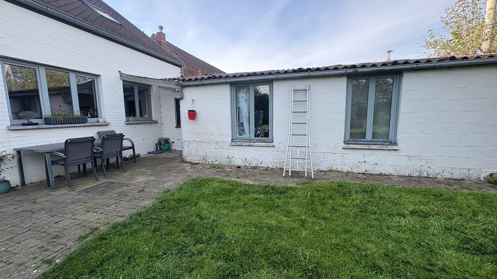 Bungalow à la façade blanche décrépite et vieille toiture en tôles